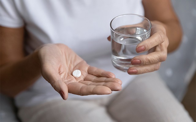 Frau mit Tablette und Wasser in den Händen